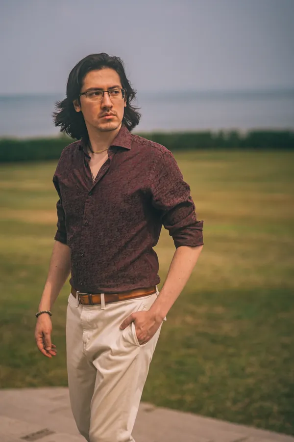 Man in a patterned shirt standing by the water