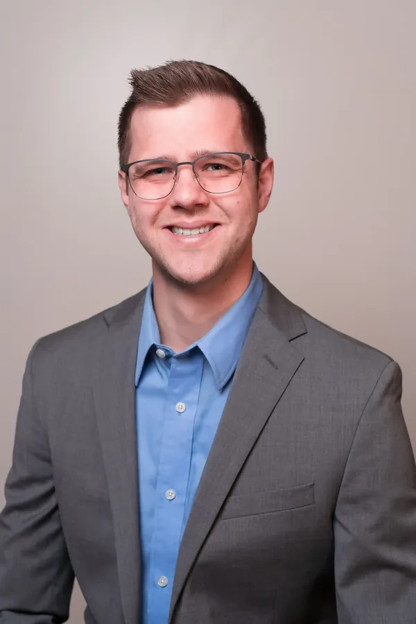 Studio headshot in a grey blazer
