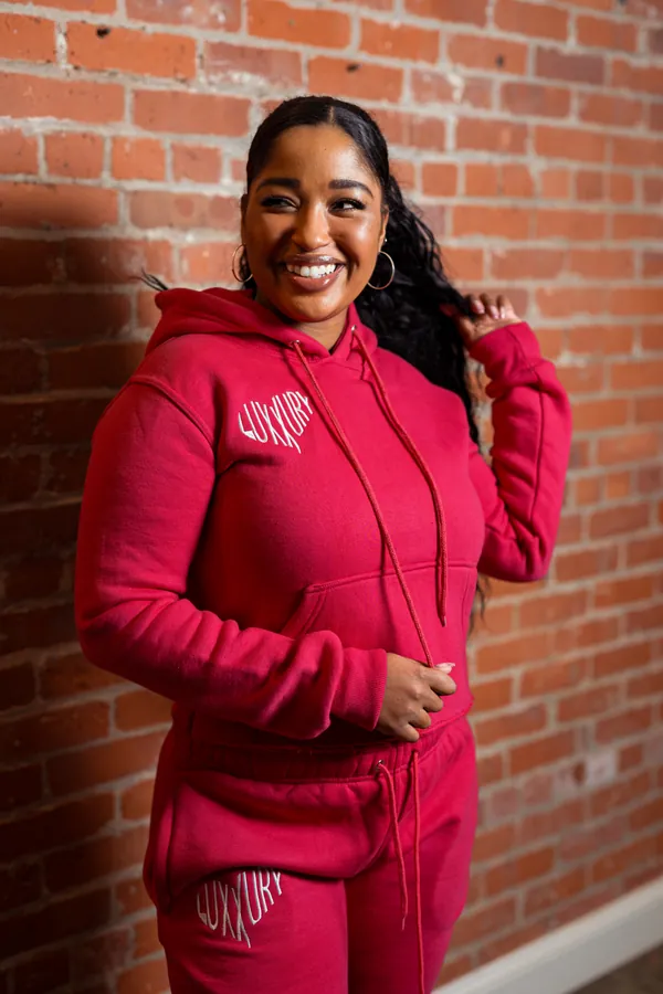 Model in a red tracksuit against brick