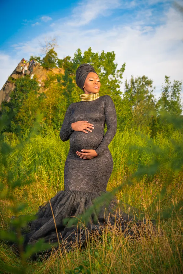 Expecting mother in a green gown among tall grass