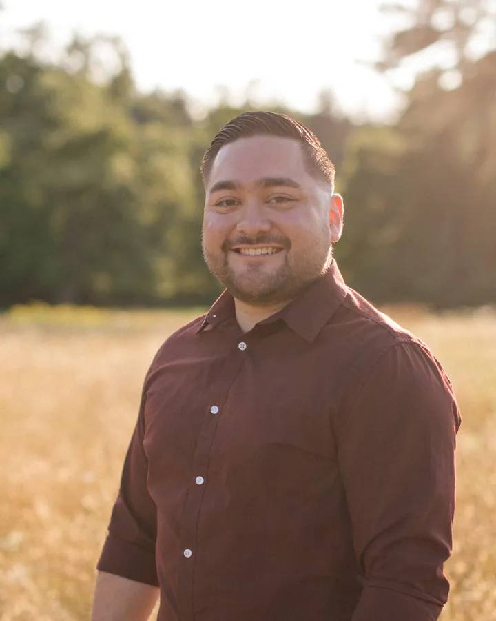 Axel Del Cid smiling in a golden field at sunset